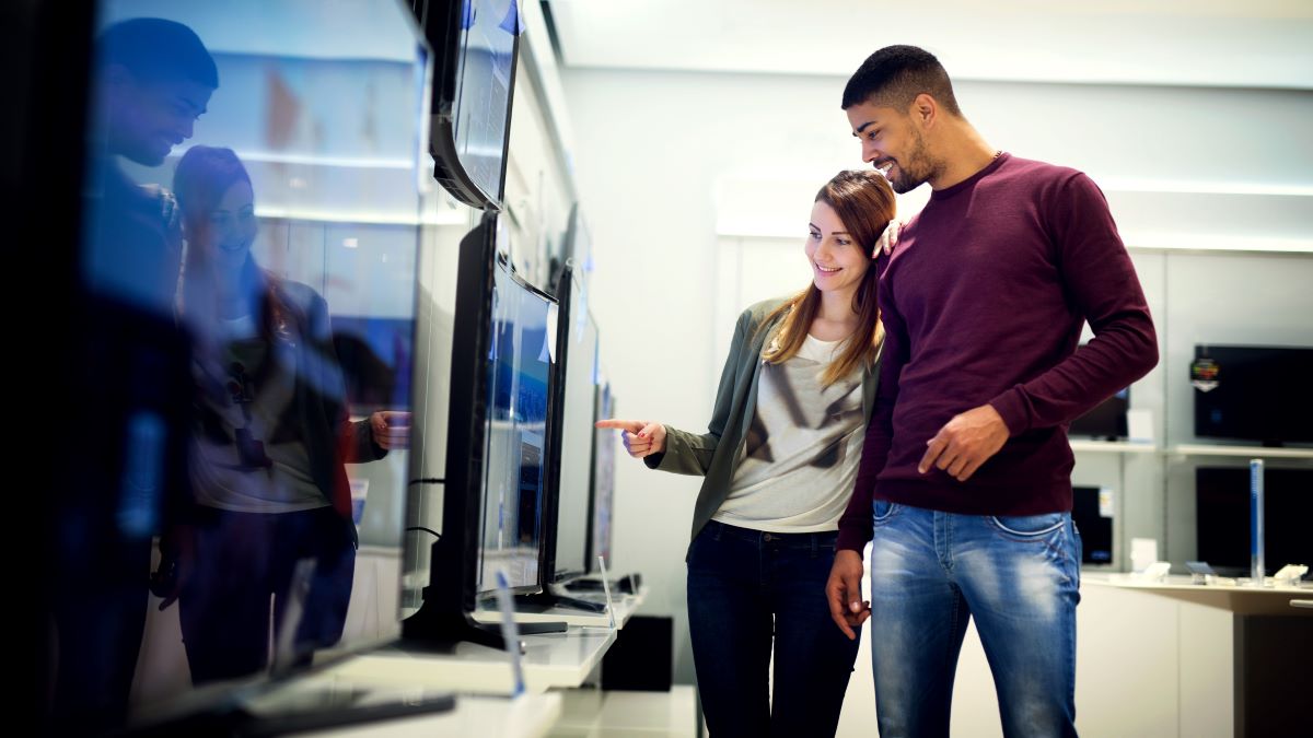 young couple looking at new flat-screen TVs in store