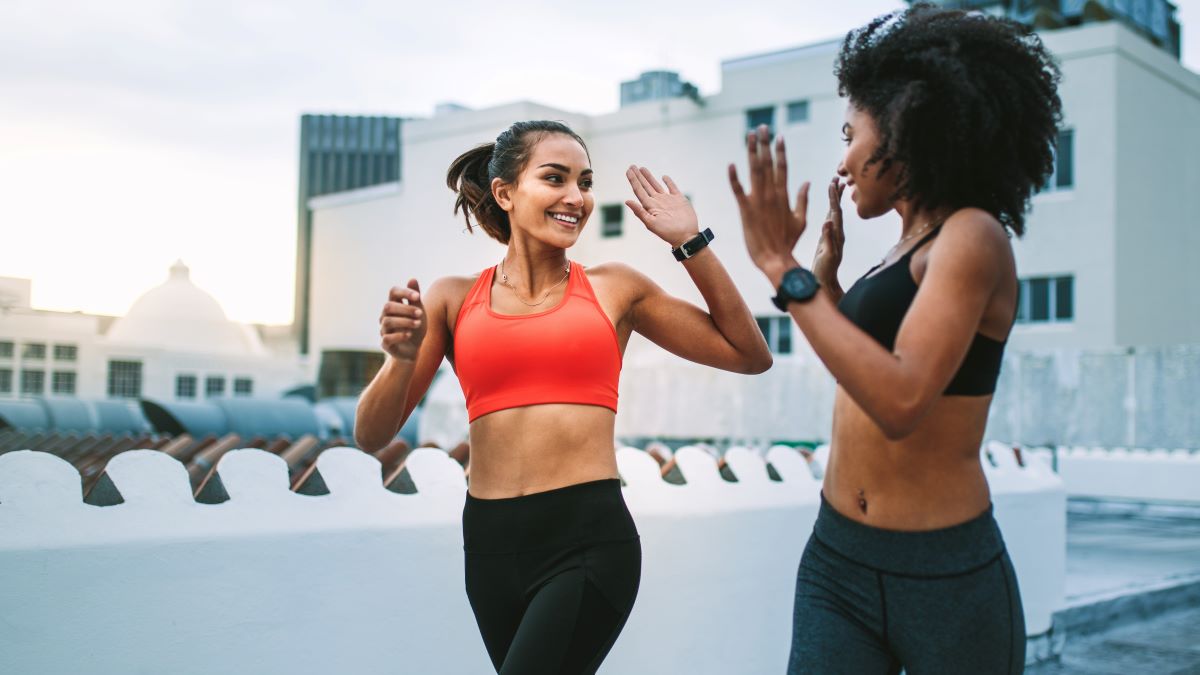 young women giving each other high five while running together
