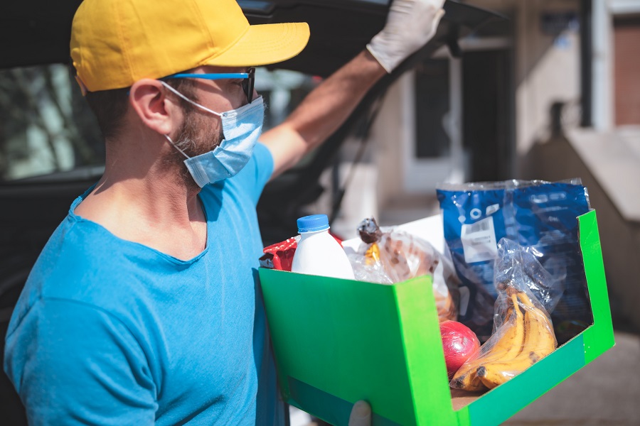 Man carrying grocery delivery from van to customer's home