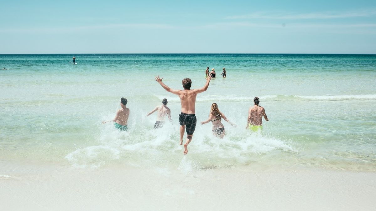 young people running into turquoise water at beach